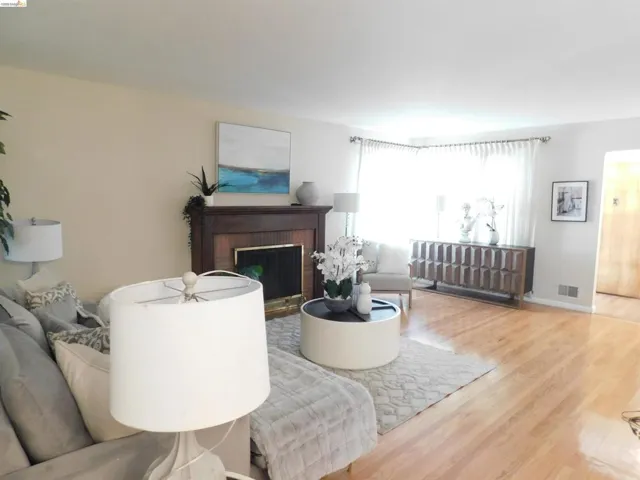 Hardwood flooring extending throughout, complemented by a prominent fireplace with a dark wood mantel and surround
