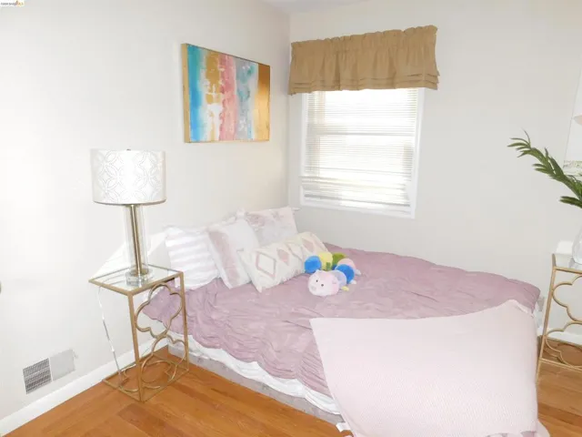 Room featuring warm wood-finish flooring and a single window with blinds