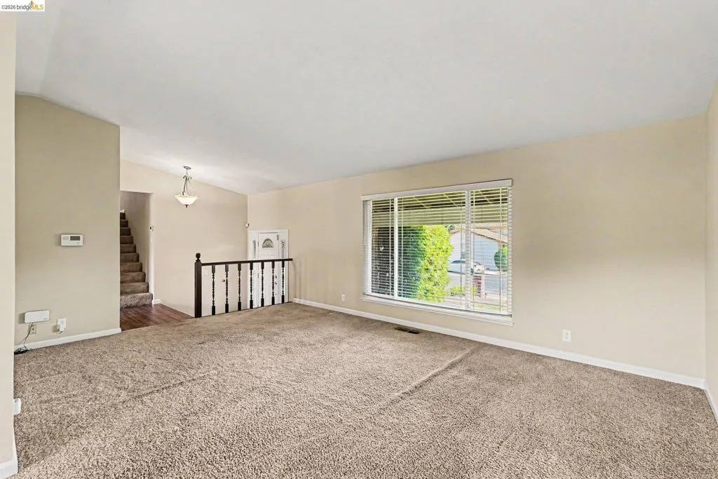Spacious living area featuring neutral carpeting and light-toned walls
