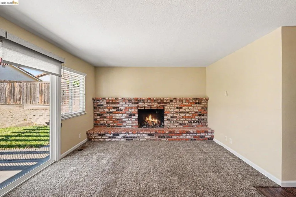 Living area featuring a brick fireplace, sliding glass door, and wall-to-wall carpeting