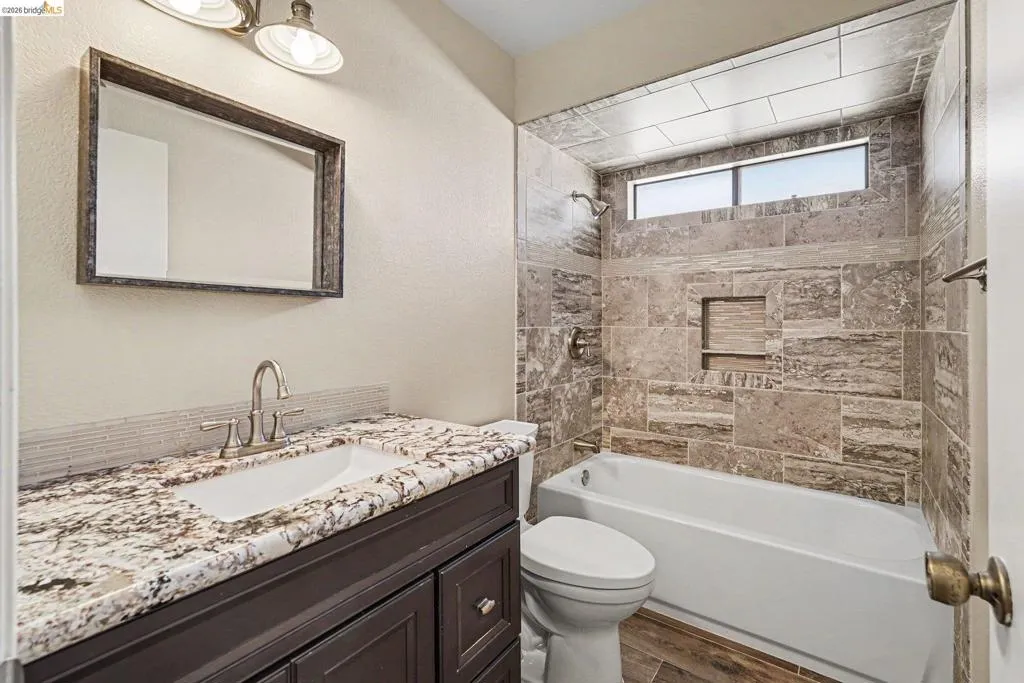 Bathroom with a dark wood-finish vanity, granite countertop, undermount sink, and brushed nickel faucet
