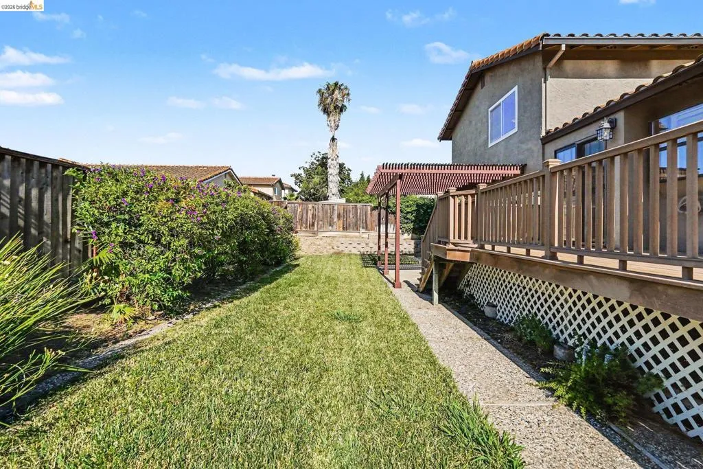Expansive backyard featuring a lush lawn, privacy fencing, and mature landscaping