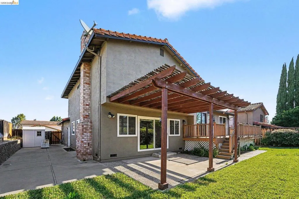 Rear exterior featuring a patio with a wooden pergola, stucco siding, and a clay tile roof
