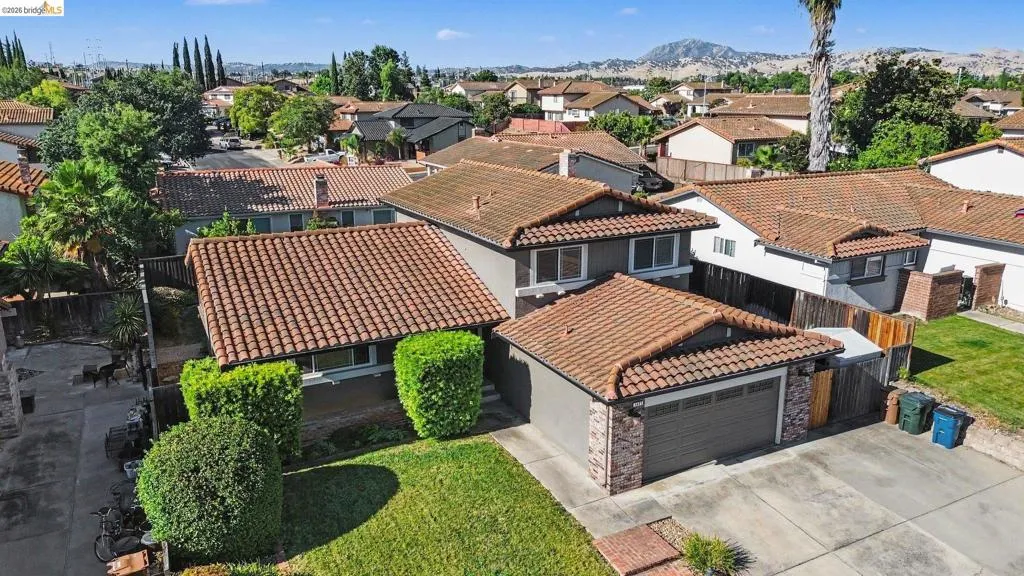 Two-story residence featuring a tile roof, an attached garage with a sectional door, and a brick facade accent