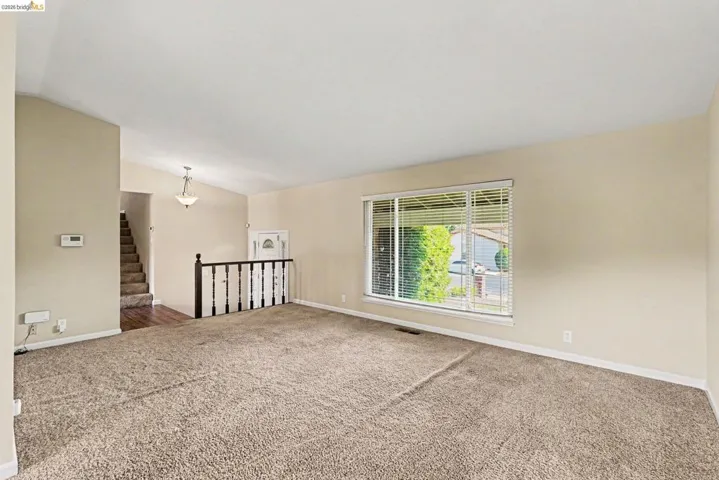 Spacious living area featuring neutral carpeting and light-toned walls
