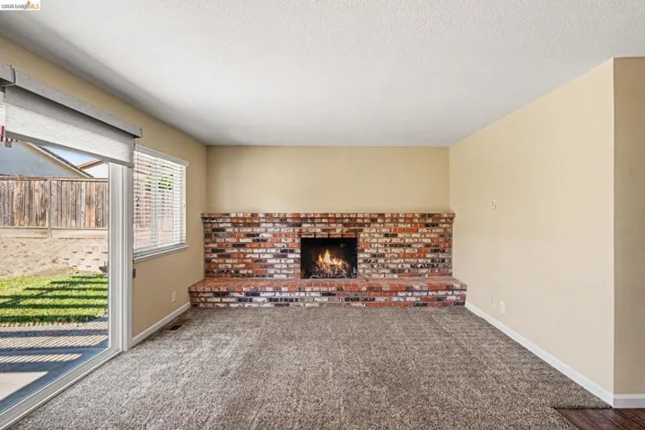 Living area featuring a brick fireplace, sliding glass door, and wall-to-wall carpeting