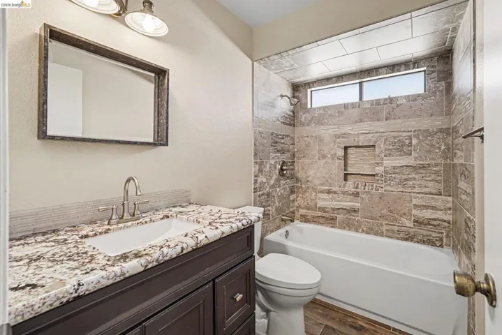 Bathroom with a dark wood-finish vanity, granite countertop, undermount sink, and brushed nickel faucet