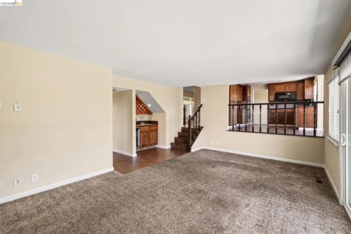 Carpeted living area featuring a built-in wet bar with wine storage, wood-finish flooring, and a sliding glass door