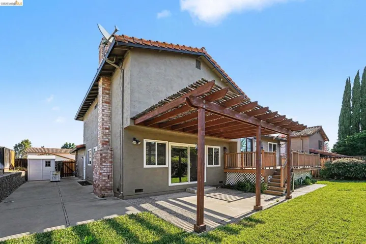 Rear exterior featuring a patio with a wooden pergola, stucco siding, and a clay tile roof