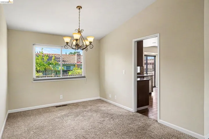 Carpeted room featuring a decorative chandelier with four amber-toned lights