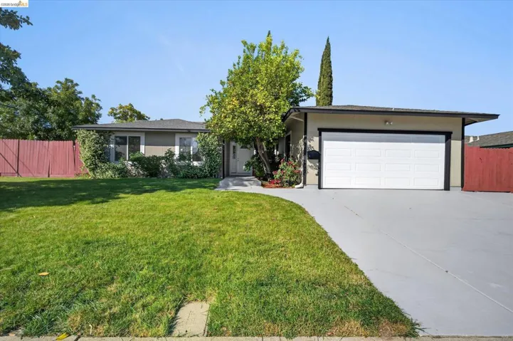 Single-story residence featuring a front lawn and paved driveway