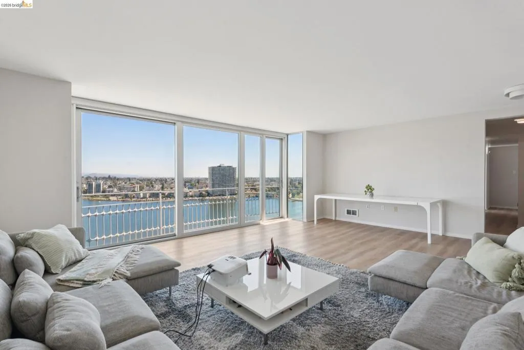 Living area with a wall of windows, a water view, and wood finished floors