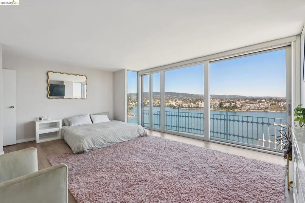 Bedroom featuring a water view, expansive windows, wood finished floors, and access to exterior