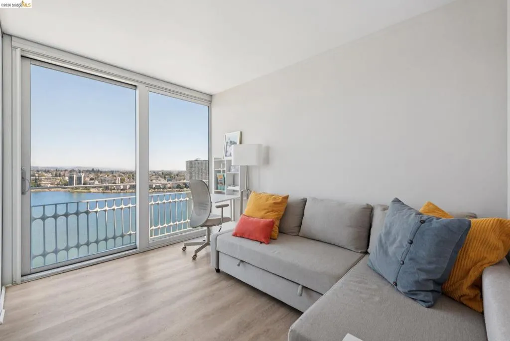 Living room with a water view, expansive windows, and wood finished floors