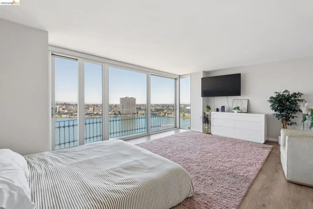 Bedroom with a wall of windows, wood finished floors, and access to exterior
