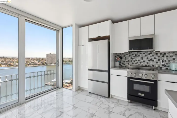 Kitchen with floor to ceiling windows, appliances with stainless steel finishes, white cabinets, a water view, and backsplash