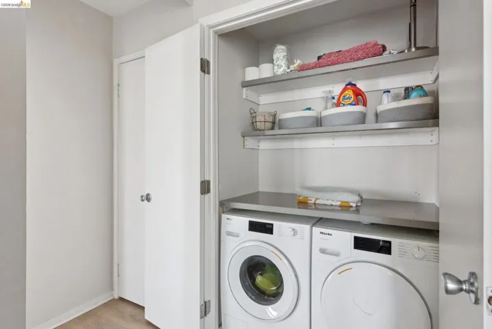 Laundry area with washing machine and dryer and light wood finished floors