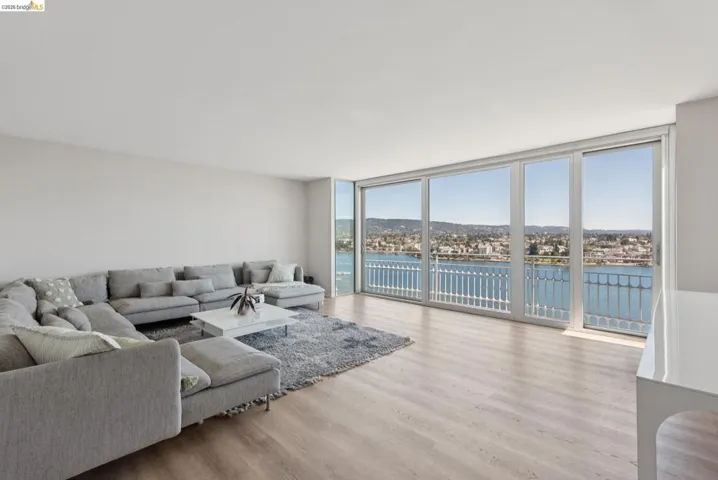 Living area featuring a wall of windows, a water view, and wood finished floors