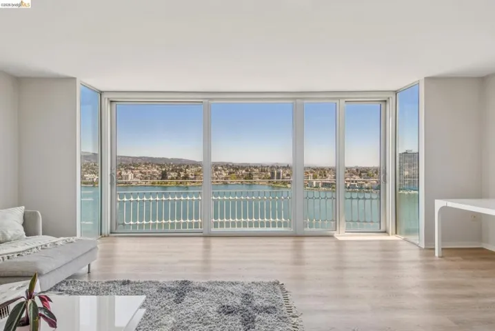 Sitting room with floor to ceiling windows, a water view, and light wood-type flooring