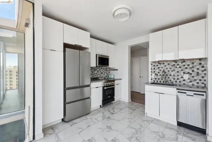 Kitchen featuring dark countertops, stainless steel appliances, tasteful backsplash, and white cabinets