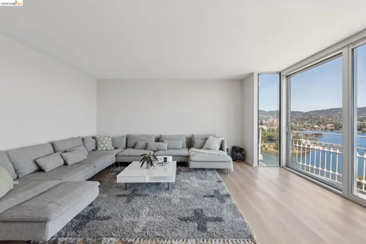 Living area with a water view, floor to ceiling windows, and wood finished floors