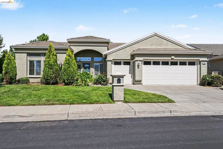 Stucco exterior with a tile roof, featuring a concrete driveway and an attached two-car garage