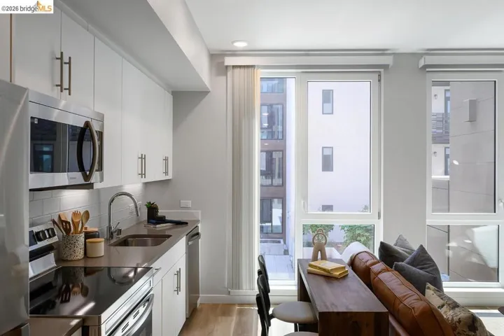 Kitchen with stainless steel appliances, plenty of natural light, light wood-style flooring, and white cabinetry