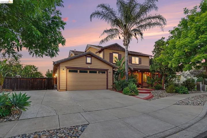 Two-story residence featuring a two-car garage with carriage-style doors, a concrete driveway, and mature landscaping