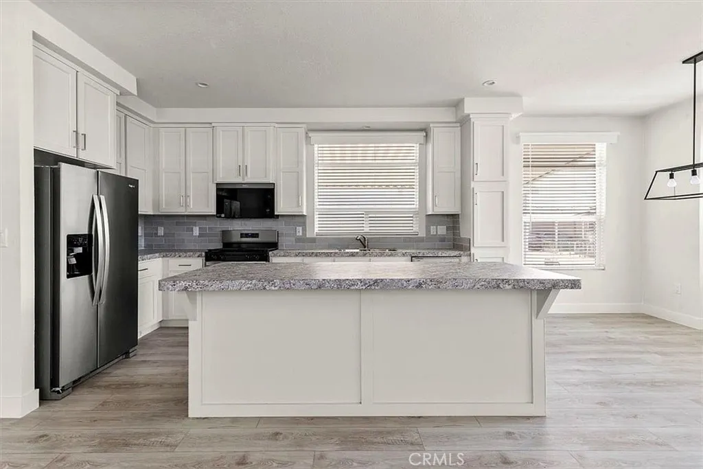 Kitchen: Open island kitchen with white cabinetry, stainless steel appliances, bar seating, recessed lighting, and seamless flow to the living and dining areas.