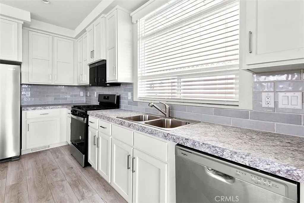 Kitchen: Open island kitchen with white cabinetry, stainless steel appliances, bar seating, recessed lighting, and seamless flow to the living and dining areas.
