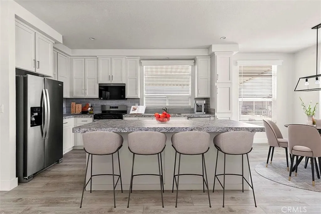 Kitchen: Open island kitchen with white cabinetry, stainless steel appliances, bar seating, recessed lighting, and seamless flow to the living and dining areas.