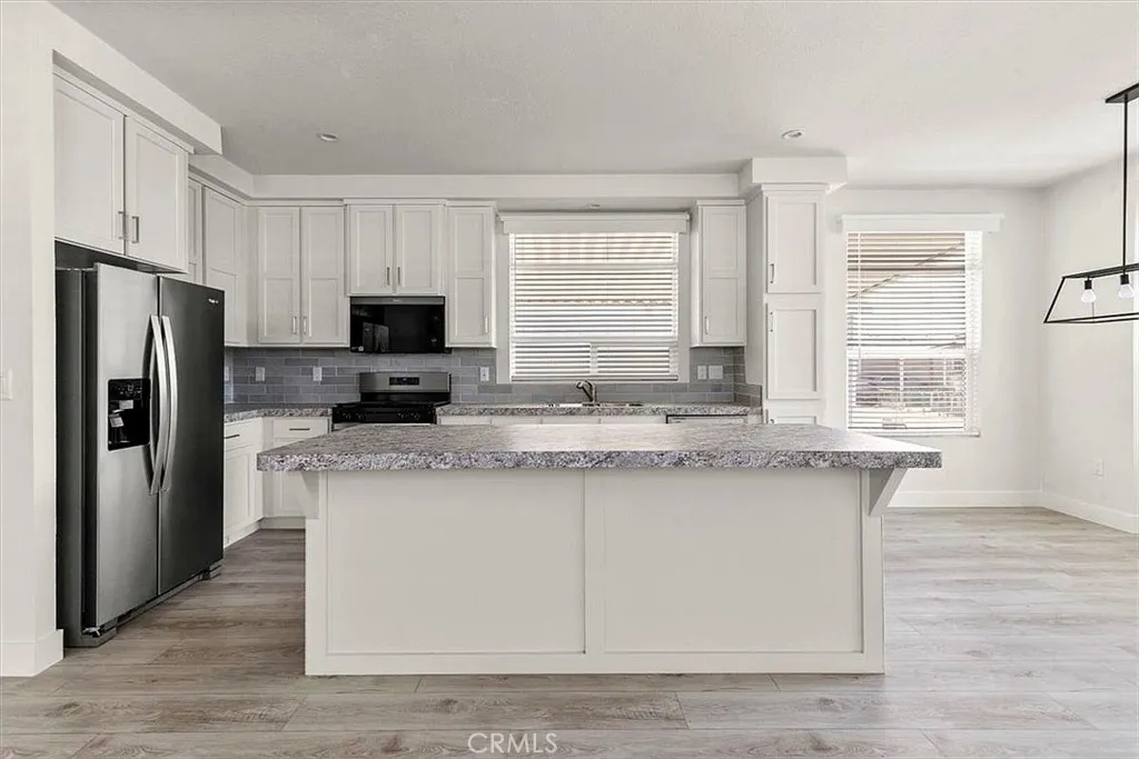 Kitchen: Open island kitchen with white cabinetry, stainless steel appliances, bar seating, recessed lighting, and seamless flow to the living and dining areas.