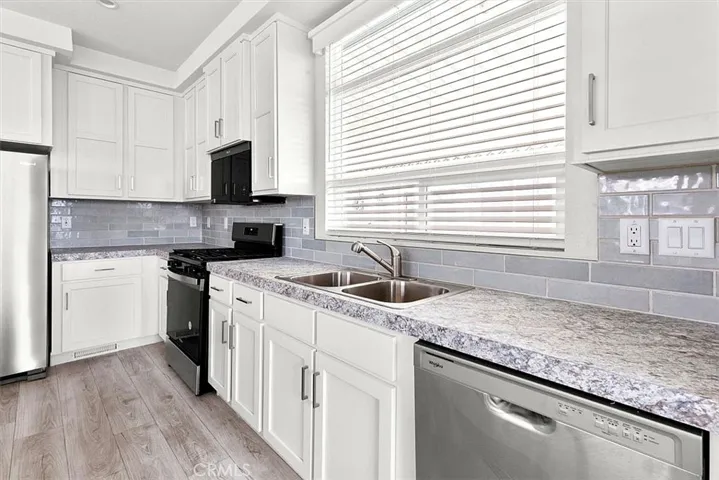Kitchen: Open island kitchen with white cabinetry, stainless steel appliances, bar seating, recessed lighting, and seamless flow to the living and dining areas.