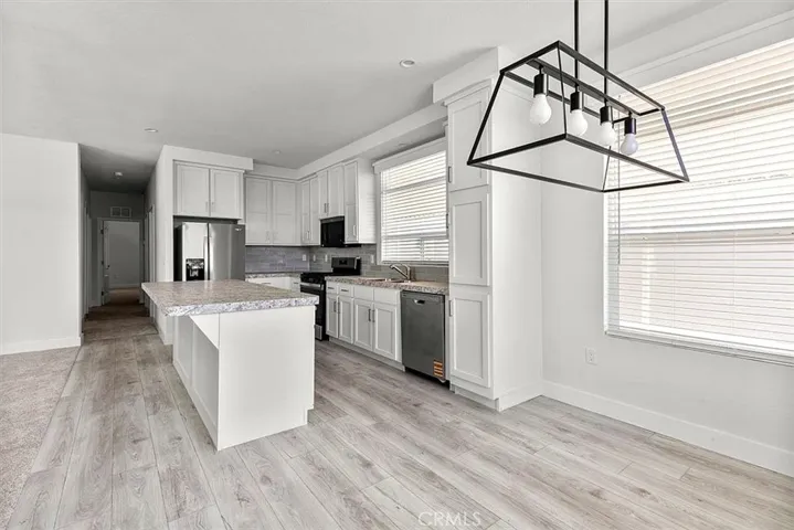  Kitchen: Open island kitchen with white cabinetry, stainless steel appliances, bar seating, recessed lighting, and seamless flow to the living and dining areas.