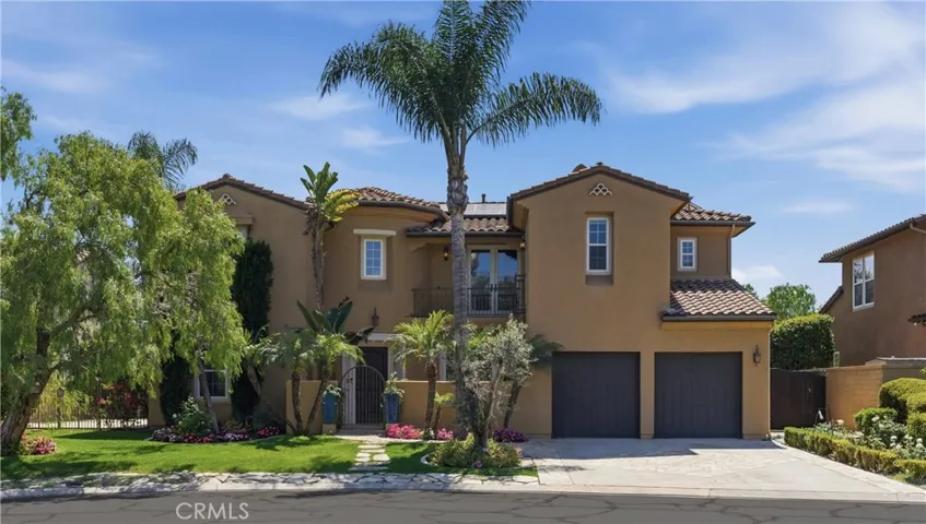 Stunning Rancho Madrina residence showcasing timeless Mediterranean-inspired architecture, manicured landscaping, mature palms, and an inviting gated courtyard entry.