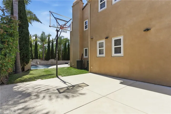 Dedicated sport court area with basketball hoop and additional side yard space