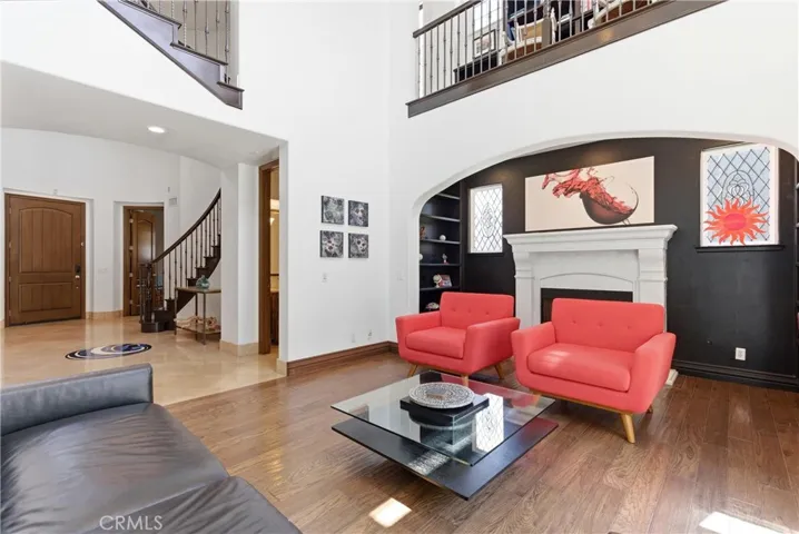 Open-concept formal living area featuring soaring ceilings, rich hardwood flooring, custom built-ins, oversized windows, and architectural archways.