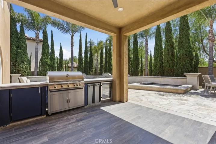 Outdoor kitchen with built-in BBQ, beverage refrigerator, storage, and serving bar