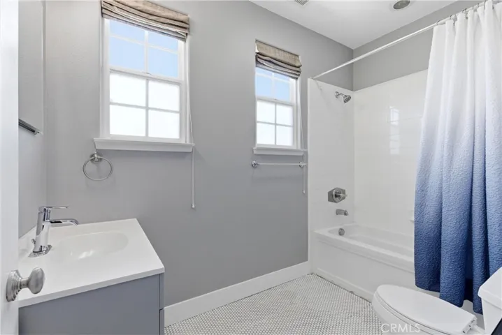 Secondary full bath with clean, timeless finishes including white tile surround, updated vanity, and abundant natural light