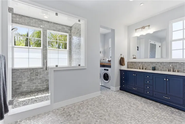 Fully remodeled spa-inspired primary bath featuring dual vanities, designer finishes, oversized walk-in shower, soaking tub, and custom tilework.