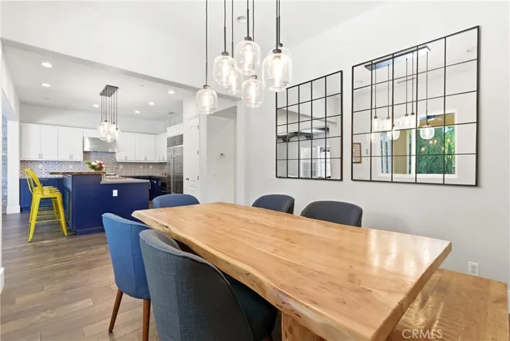 Open dining room with designer pendant lighting, wide-plank flooring, oversized windows, and contemporary entertaining space.