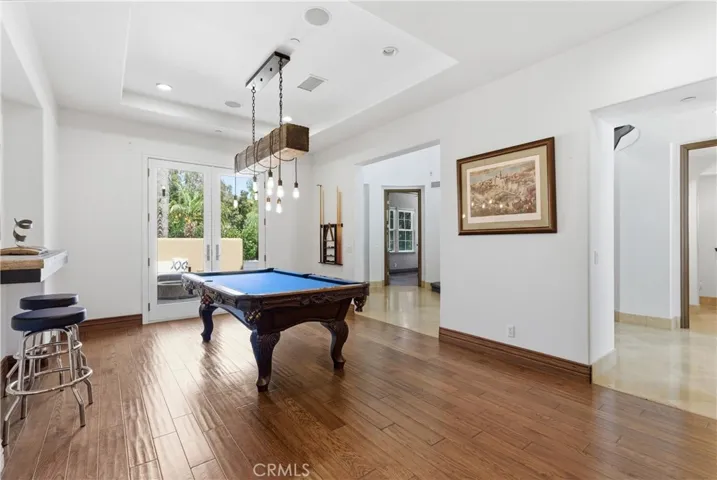 Spacious recreation room with pool table, custom lighting, French doors to the outdoor entertaining area, and seamless connection to the main living spaces.