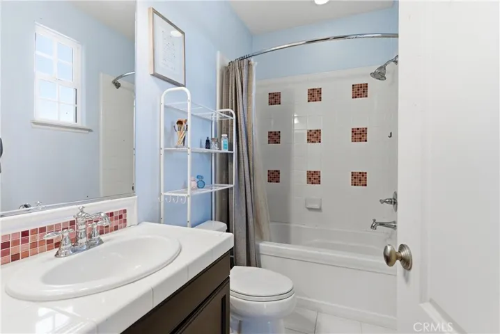 Additional full bathroom with blue accent walls, white tile vanity, tub/shower combination, and decorative tile accents.