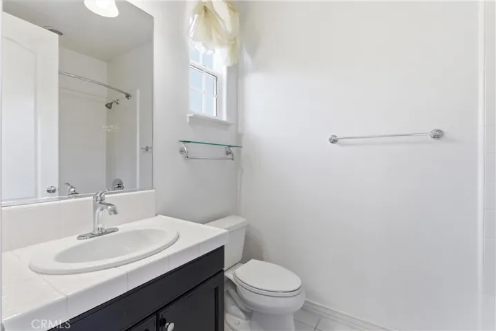 Full bathroom with white tile vanity, tub/shower combination, and accent tile detailing.