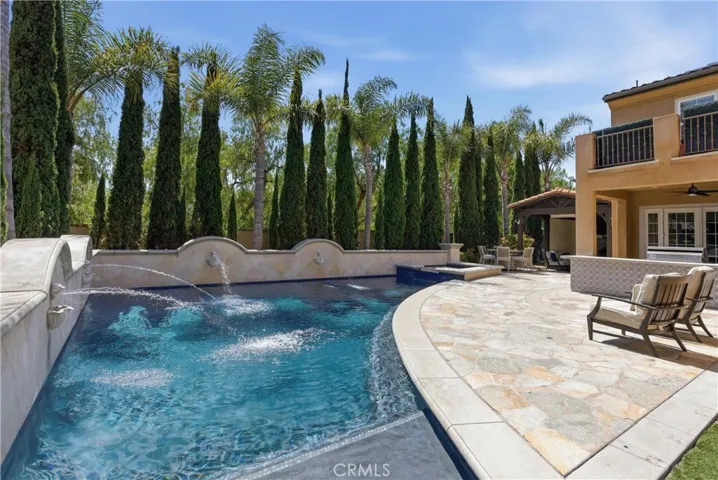 Private backyard framed by mature palms and towering cypress trees