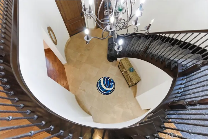 Dramatic curved staircase and soaring two-story entry create an unforgettable first impression, highlighted by wrought-iron detailing, rich wood accents, and statement chandelier lighting