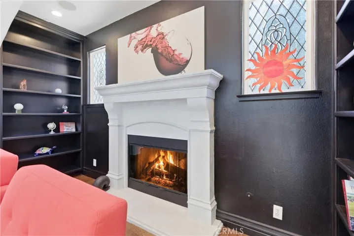 Designer fireplace detail with custom mantel, black accent walls, built-in shelving, leaded glass windows, and warm contemporary styling