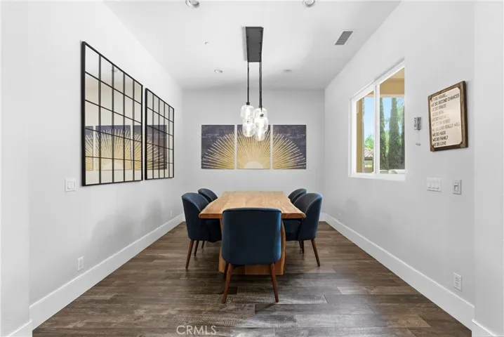 Modern dining area featuring custom lighting, live-edge wood dining table, contemporary finishes, and open flow to the remodeled kitchen.