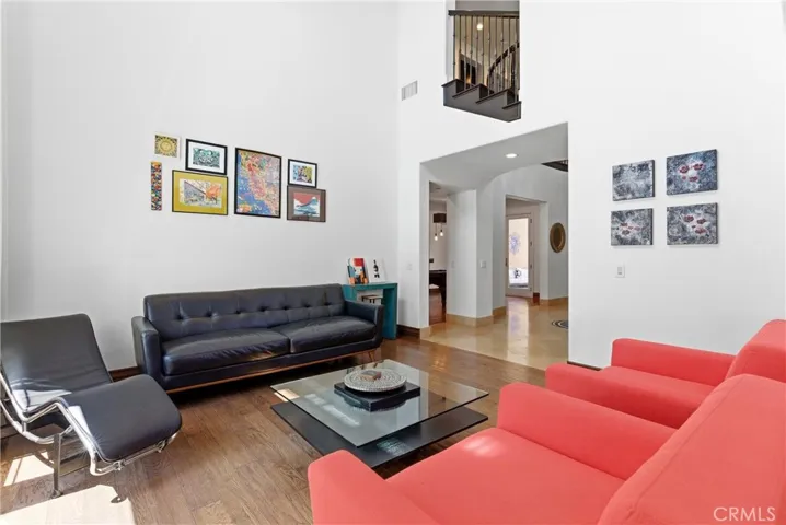 Spacious formal living room with vaulted ceilings, hardwood floors, gallery-style walls, modern fireplace, and abundant natural light throughout.
