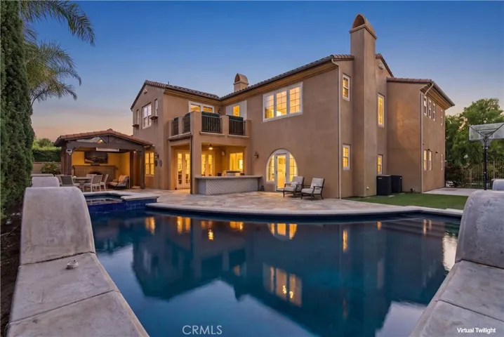 Resort-style backyard designed for elevated entertaining, featuring a sparkling pool and spa, covered outdoor cabana with built-in fireplace, multiple lounge and dining areas, and seamless indoor-outdoor flow.
